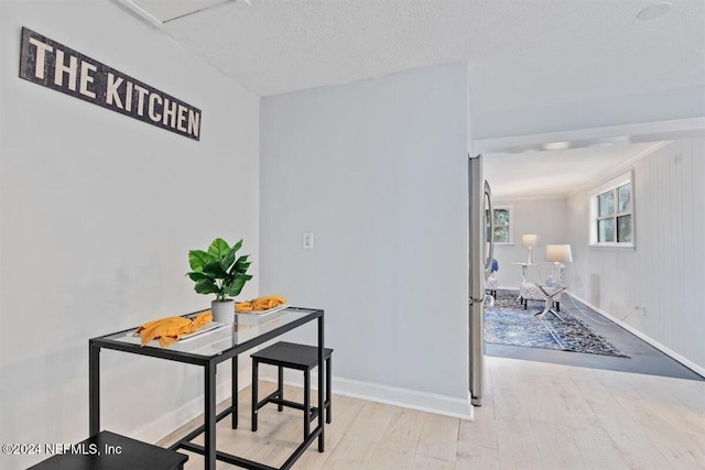 dining space with wood walls, a textured ceiling, and light wood-type flooring