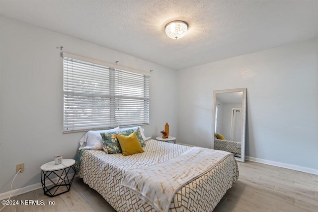 bedroom with light hardwood / wood-style floors and a textured ceiling