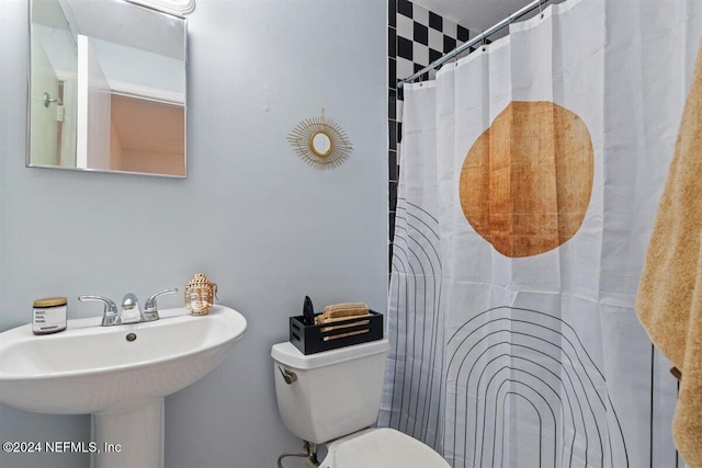 bathroom with toilet, sink, and a shower with curtain