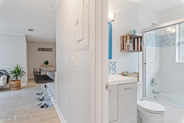 full bathroom featuring wood-type flooring, enclosed tub / shower combo, toilet, vanity, and ornamental molding