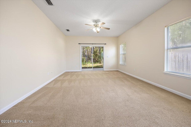 empty room with a textured ceiling, ceiling fan, and light colored carpet