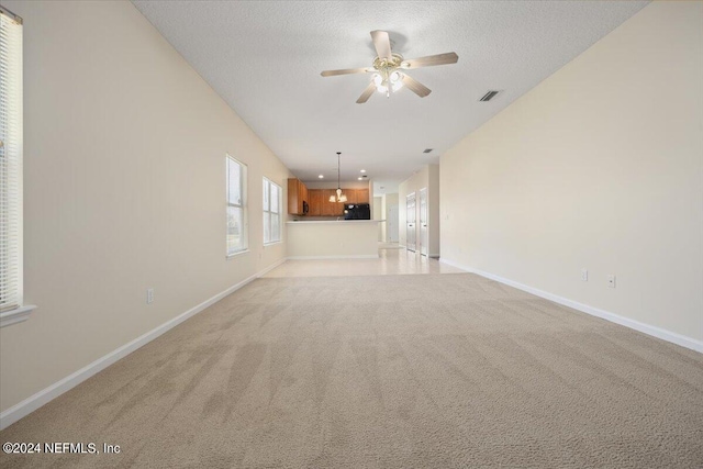 unfurnished living room featuring ceiling fan, a textured ceiling, and light carpet