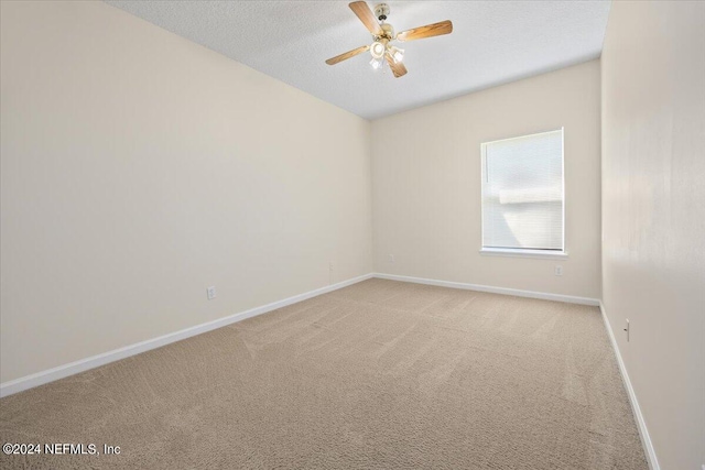 carpeted spare room with ceiling fan and a textured ceiling