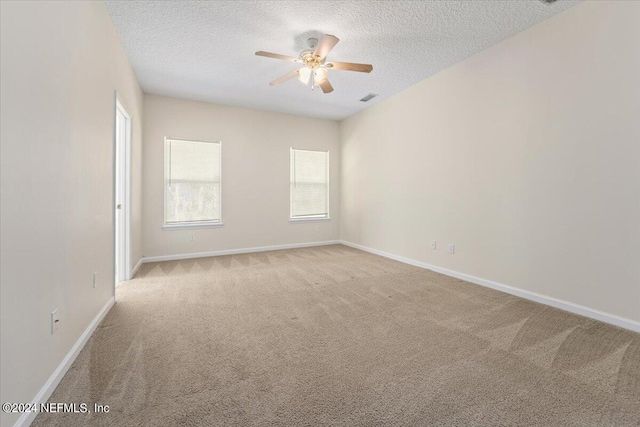 empty room with ceiling fan, light carpet, and a textured ceiling