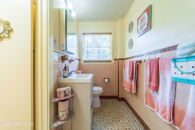 bathroom featuring tile patterned flooring, vanity, tile walls, and toilet