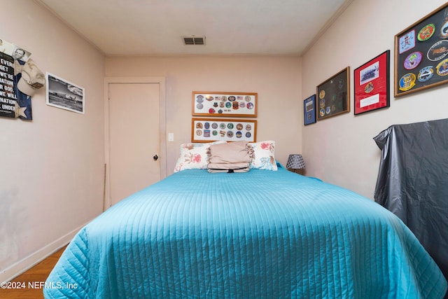 bedroom with wood-type flooring and ornamental molding