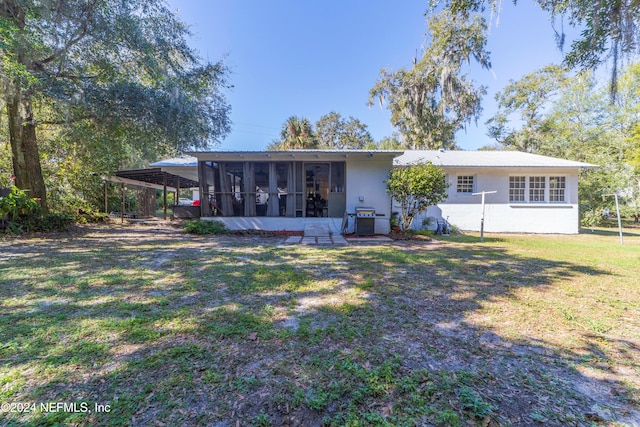 rear view of house featuring a sunroom, a yard, and a carport