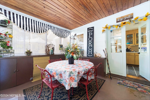 dining space featuring wood ceiling, concrete floors, and ornamental molding