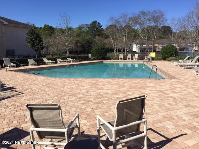 community pool with a patio and fence