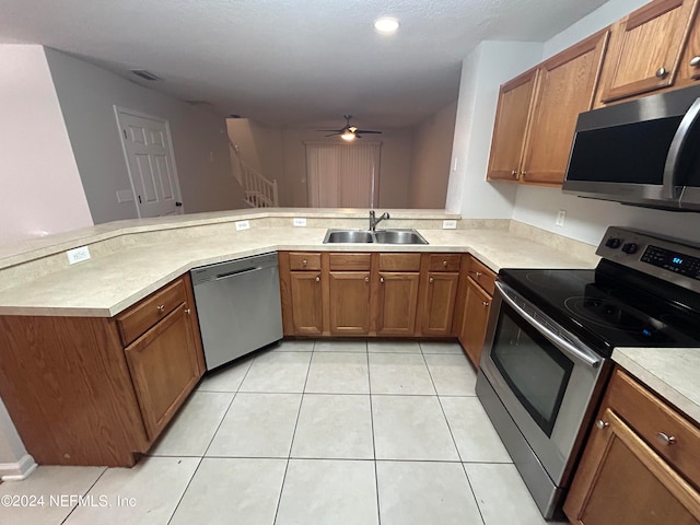 kitchen featuring sink, light tile patterned floors, kitchen peninsula, ceiling fan, and stainless steel appliances