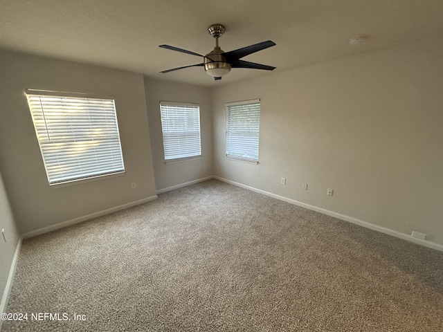 carpeted spare room featuring ceiling fan, baseboards, and a smoke detector