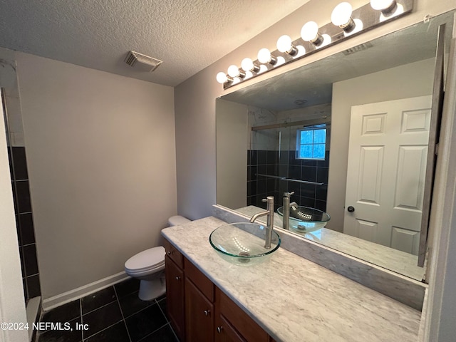 bathroom with vanity, toilet, a shower with door, tile patterned floors, and a textured ceiling