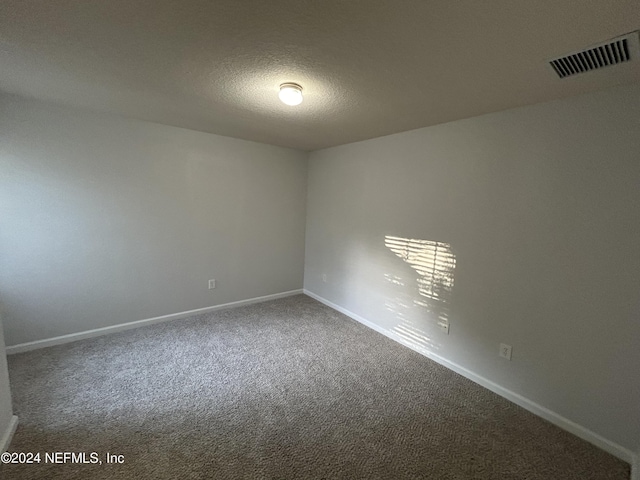 spare room featuring carpet, baseboards, and a textured ceiling