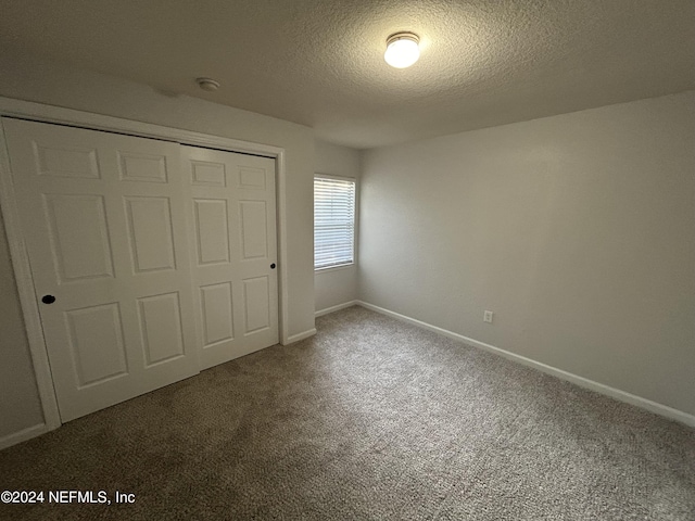 unfurnished bedroom featuring carpet floors, a textured ceiling, a closet, and baseboards
