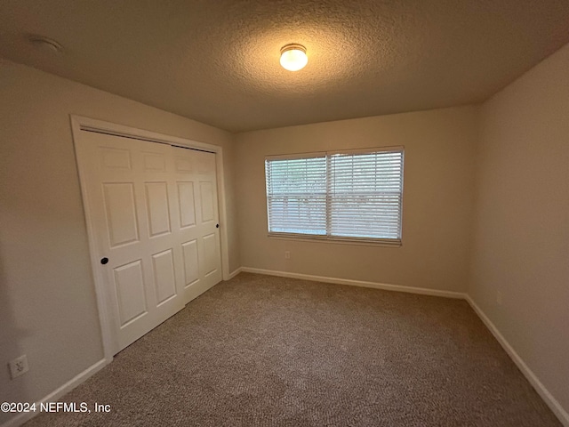 unfurnished bedroom with a closet, a textured ceiling, and carpet