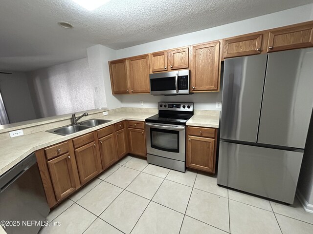 kitchen with appliances with stainless steel finishes, sink, a textured ceiling, and light tile patterned floors