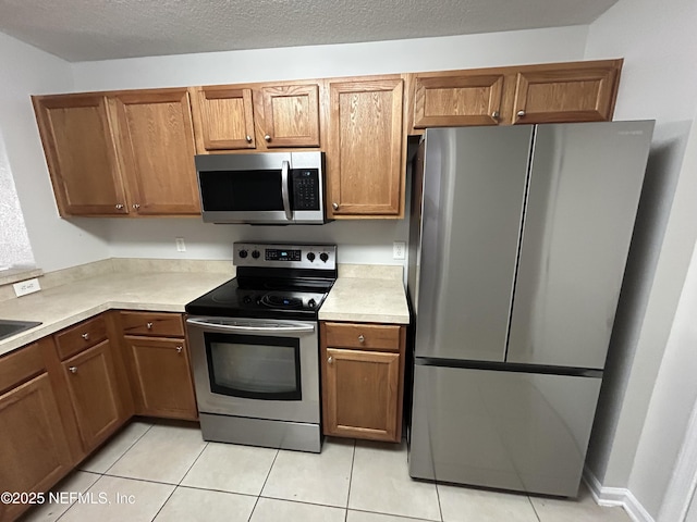 kitchen featuring light tile patterned floors, a textured ceiling, and appliances with stainless steel finishes