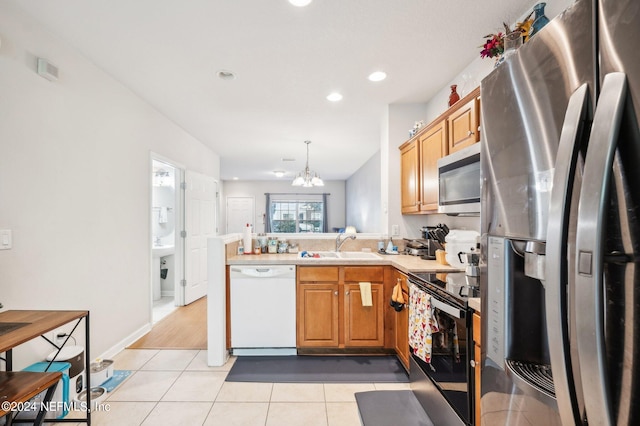 kitchen featuring kitchen peninsula, sink, light tile patterned flooring, pendant lighting, and appliances with stainless steel finishes