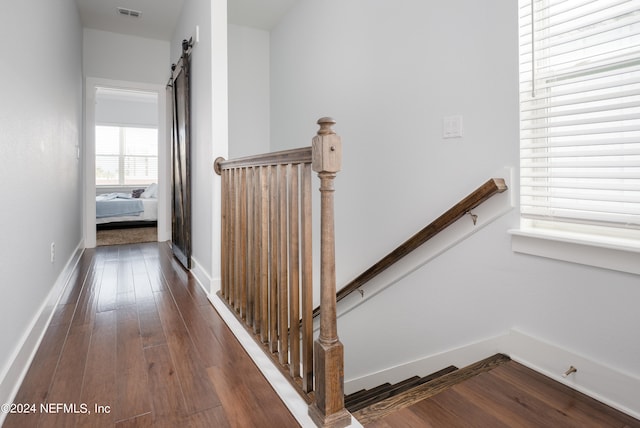 staircase featuring a barn door and wood-type flooring