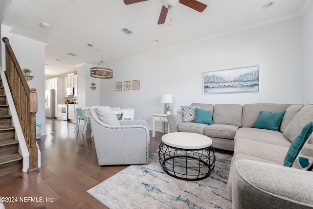 living room with ceiling fan with notable chandelier, dark hardwood / wood-style floors, and ornamental molding