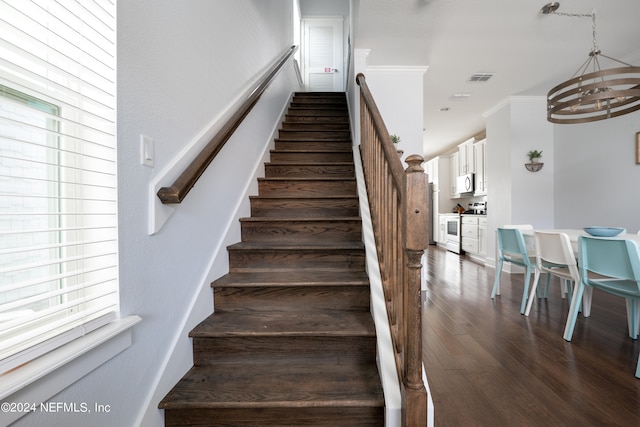 stairs with hardwood / wood-style floors and a notable chandelier