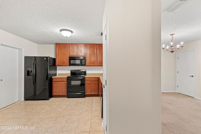 kitchen featuring a textured ceiling, light tile patterned floors, black appliances, and a notable chandelier