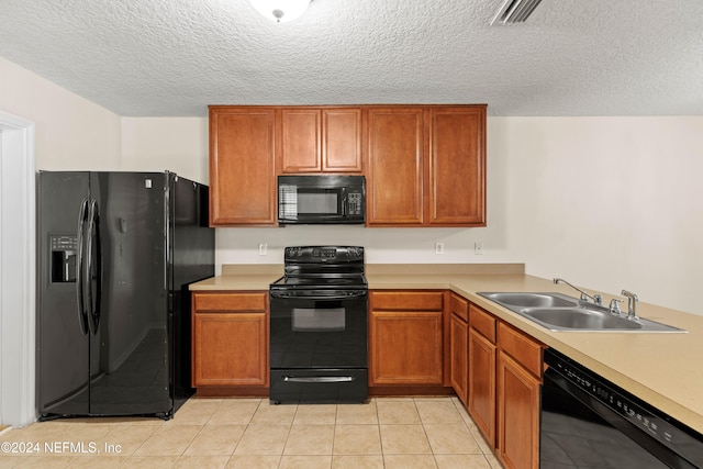 kitchen with black appliances, sink, light tile patterned flooring, and a textured ceiling