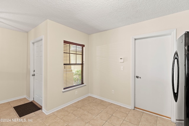 empty room featuring a textured ceiling and light tile patterned flooring