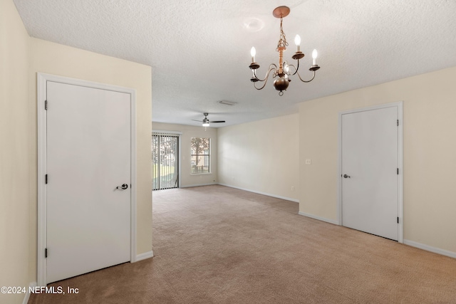 carpeted empty room featuring ceiling fan with notable chandelier and a textured ceiling