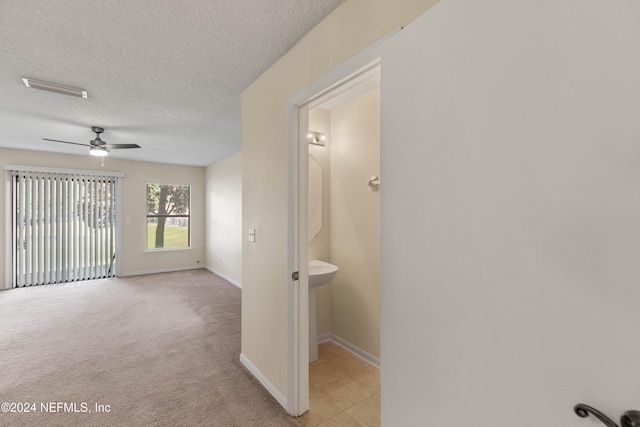 hall with a textured ceiling and light carpet