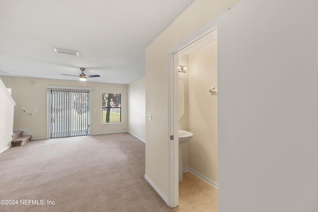 interior space featuring a textured ceiling, light colored carpet, and ceiling fan