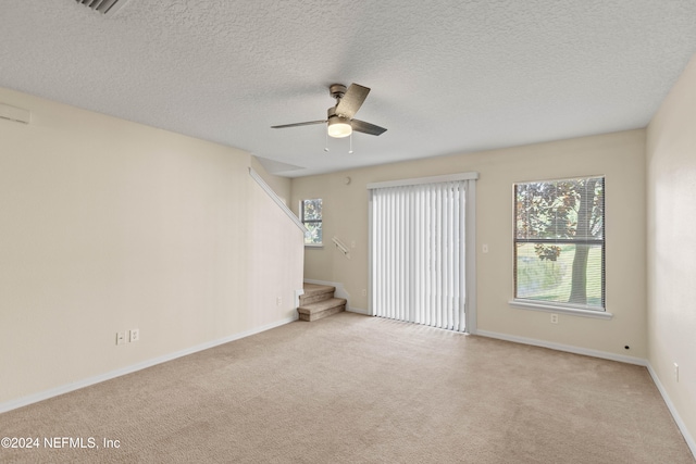 spare room featuring a textured ceiling, light colored carpet, and ceiling fan