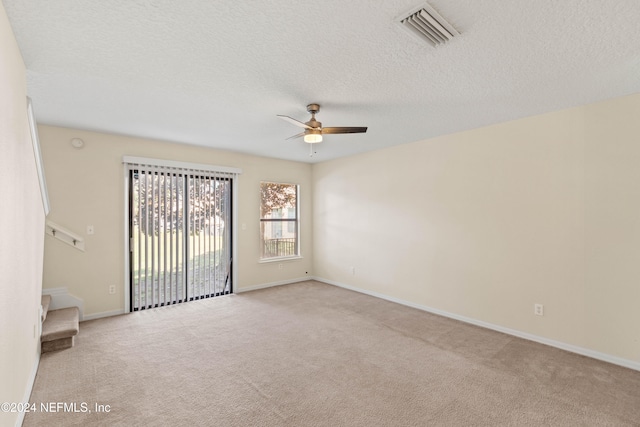 empty room featuring ceiling fan, a textured ceiling, and light carpet