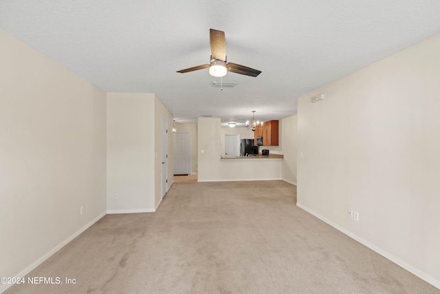 unfurnished living room featuring ceiling fan with notable chandelier, light colored carpet, and a textured ceiling