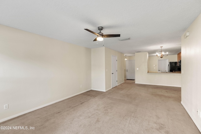 unfurnished living room featuring ceiling fan with notable chandelier, light colored carpet, and a textured ceiling