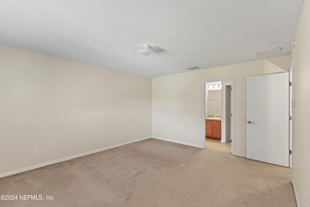 unfurnished room featuring a textured ceiling and light carpet