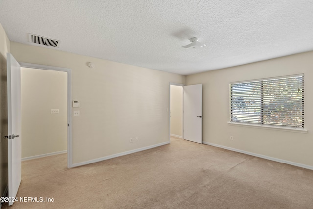 empty room with a textured ceiling and light carpet