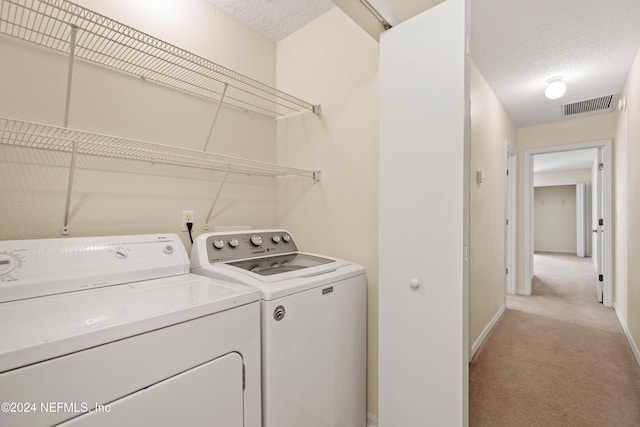 laundry area with light colored carpet, a textured ceiling, and independent washer and dryer