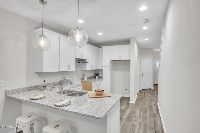 kitchen with light stone countertops, hanging light fixtures, sink, and white cabinetry