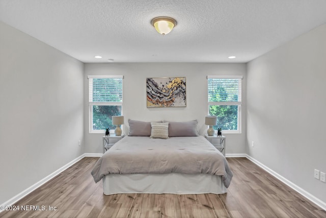 bedroom with hardwood / wood-style floors, multiple windows, and a textured ceiling