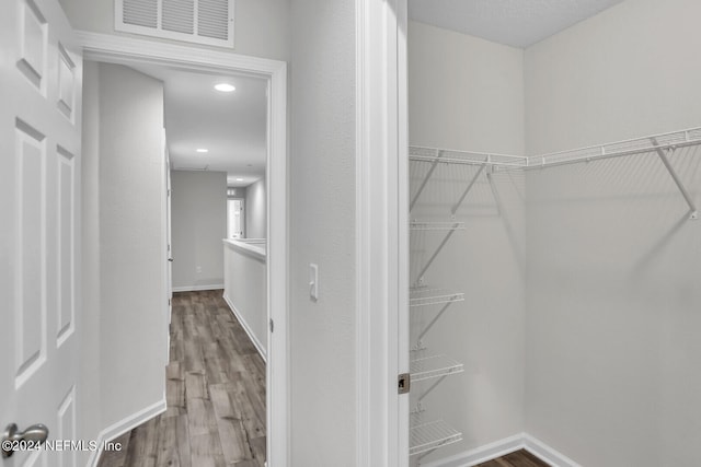 walk in closet with hardwood / wood-style flooring