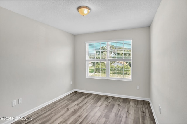 spare room featuring hardwood / wood-style flooring and a textured ceiling