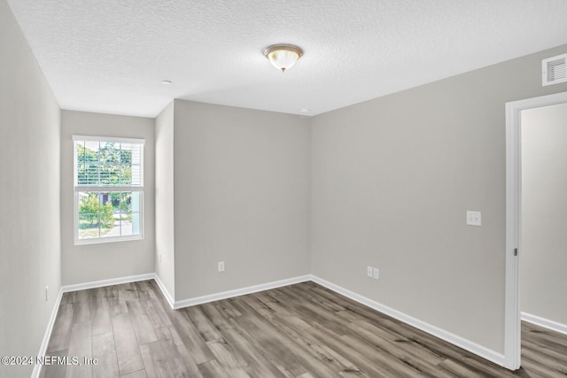 spare room featuring wood-type flooring and a textured ceiling