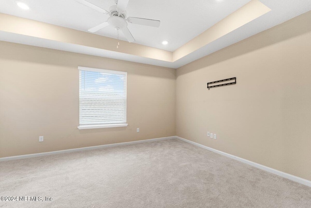 spare room with carpet floors, a tray ceiling, and ceiling fan