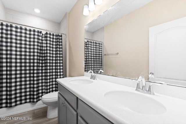 bathroom featuring wood-type flooring, walk in shower, vanity, and toilet