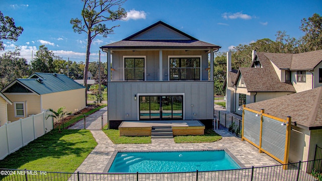 rear view of house with a fenced in pool, a lawn, and a patio area