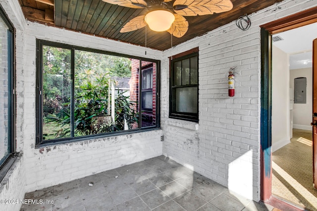 unfurnished sunroom featuring electric panel, ceiling fan, and wood ceiling