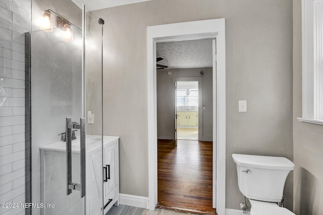 bathroom with wood-type flooring, toilet, and a shower with door