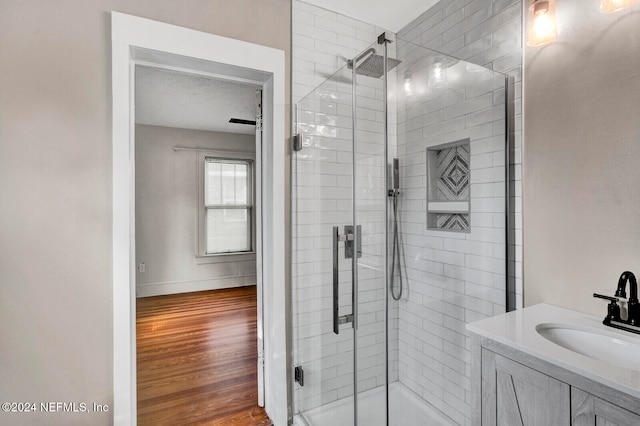 bathroom with a textured ceiling, vanity, hardwood / wood-style flooring, and a shower with door