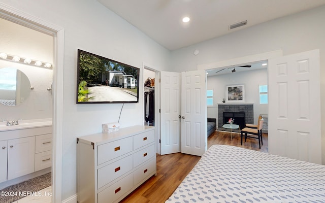 bedroom with a fireplace, ensuite bath, and light hardwood / wood-style floors